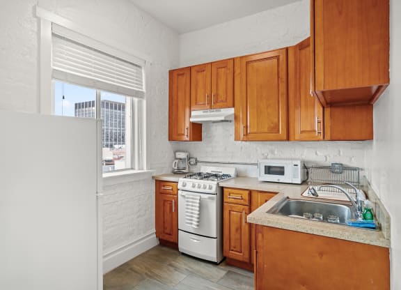 a kitchen with wooden cabinets and white appliances and a window