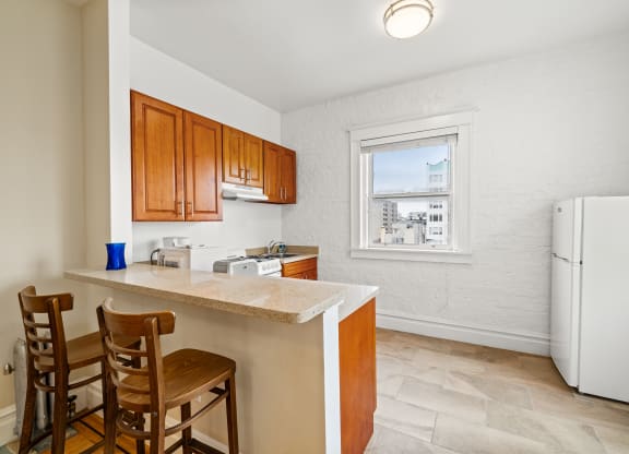 a kitchen with a counter and chairs and a refrigerator