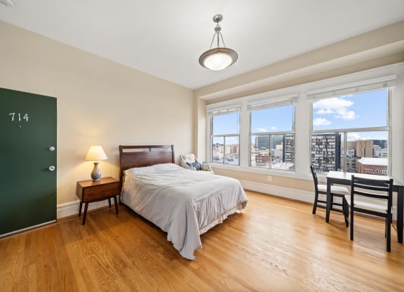 a bedroom with a bed and a large window and a desk with a chair