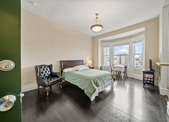 a bedroom with a bed and a chair and a window