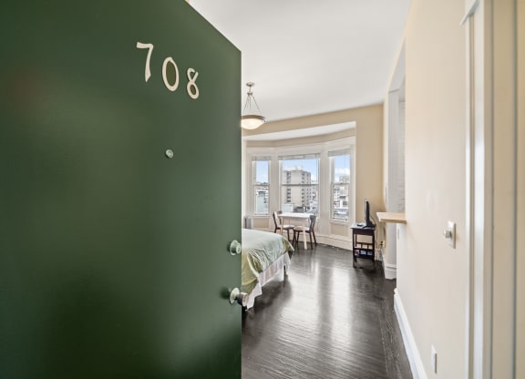 a green door leading into a bedroom with a bed and a window