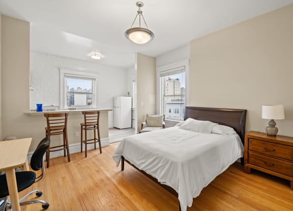 a bedroom with a bed and a kitchen with a desk and chairs