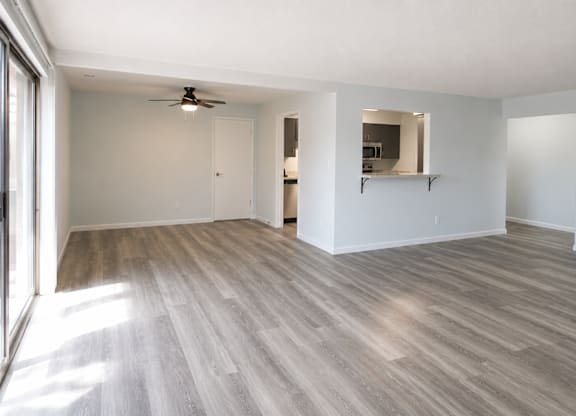 A room with a ceiling fan and light, and a wall with a mirror and a shelf.