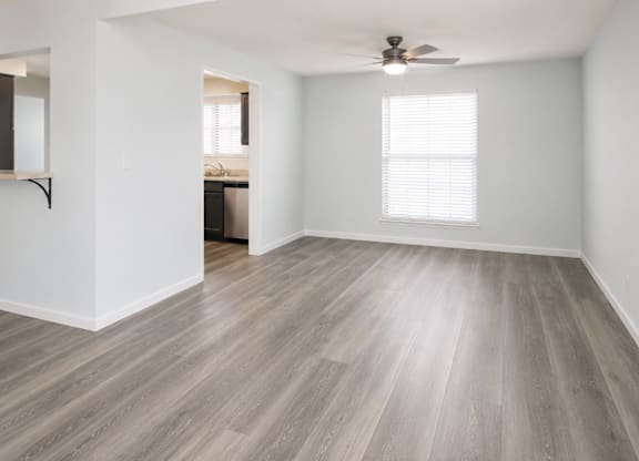 A room with a ceiling fan and a window with blinds.