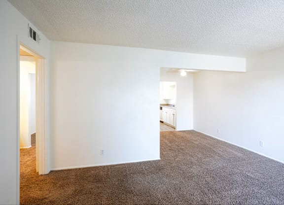 A large, empty room with carpeted flooring and white walls.