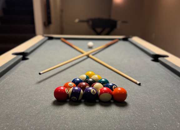 A pool table with a variety of balls and two cues.