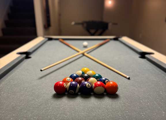 A pool table with a variety of balls and two cues.