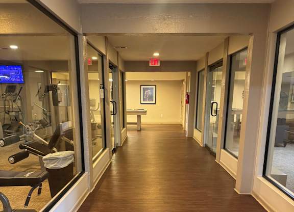A long hallway with a bench and a mirror on the wall.