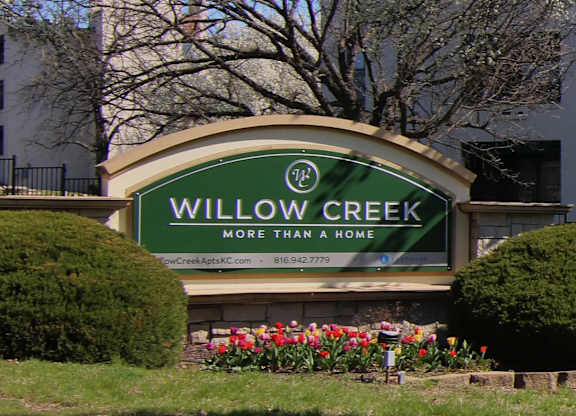 A sign that says Willow Creek in front of a building.