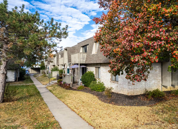 a sidewalk in front of a white brick apartment building