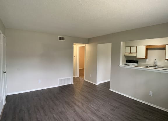 Spacious living room with vinyl flooring and open window into kitchen