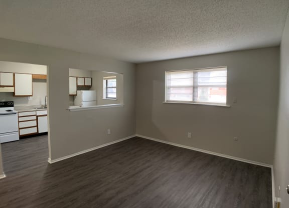 Spacious living room with vinyl flooring and open window into kitchen