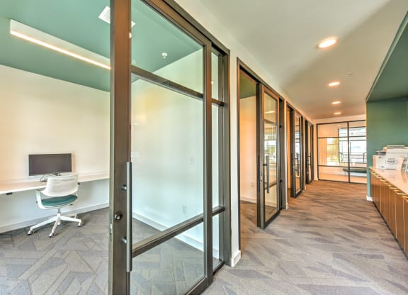 a corridor with a desk and a computer in a room with glass doors at Pinnacle Apartments, Jacksonville