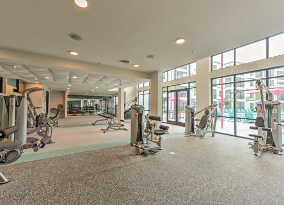 a gym with weights and other exercise equipment in a building with windows at Pinnacle Apartments, Jacksonville