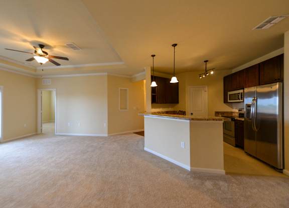 Kitchen and living room with white appliances and brown cabinets at Cabana Club - Galleria Club Apartments, Jacksonville, FL, 32256