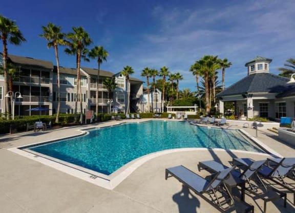 a large pool with chaise lounge chairs and palm trees in the background  at Ocean Park, Jacksonville Beach, Florida