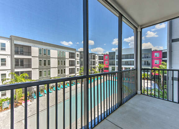 A balcony with a pool and a view of apartment buildings.