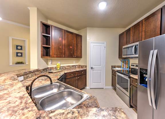 A kitchen with a granite counter top and stainless steel appliances at Cabana Club - Galleria Club Apartments, Jacksonville, FL, 32256