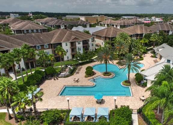 A large swimming pool surrounded by palm trees and a resort at Cabana Club - Galleria Club Apartments, Jacksonville, Florida