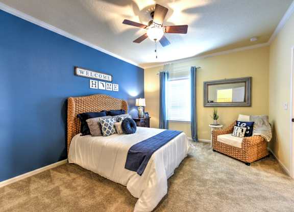A bedroom with a bed, a chair, and a ceiling fan at Cabana Club - Galleria Club Apartments, Jacksonville, FL