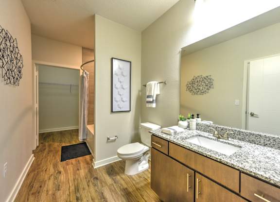 A bathroom with a toilet, sink, and mirror at Fusion Apartments, Jacksonville, FL