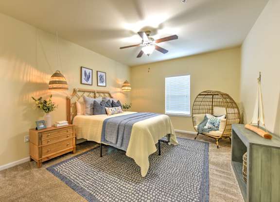 A bedroom with a bed, a chair, and a ceiling fan at Cabana Club - Galleria Club Apartments, Florida 32256