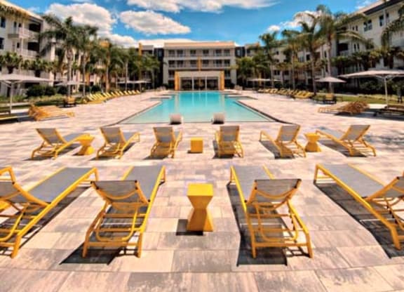 a swimming pool with yellow lounge chairs and a building in the background  at Fusion, Florida, 32256