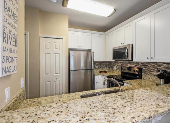 a kitchen with a granite counter top and a stainless steel refrigerator  at Ocean Park, Jacksonville Beach, 32250