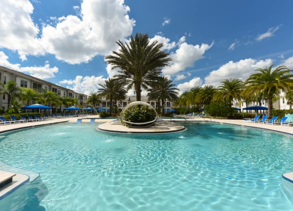 a large swimming pool with a fountain and a hotel in the background at Palm Bay Club, Florida, 32258