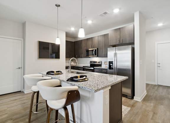 A modern kitchen with a granite countertop and stainless steel appliancesat Pinnacle Apartments, Jacksonville, FL