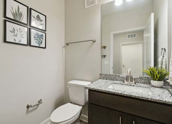 A bathroom with a toilet, sink, and mirrorat Pinnacle Apartments, Jacksonville, FL