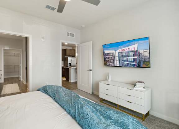 A bedroom with a bed, dresser, and a painting of a building on the wallat Pinnacle Apartments, Jacksonville, FL