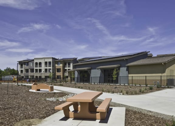 New Harmony Mutual Housing Community behind picnic table and benches on the Davis Bike Loop bike path