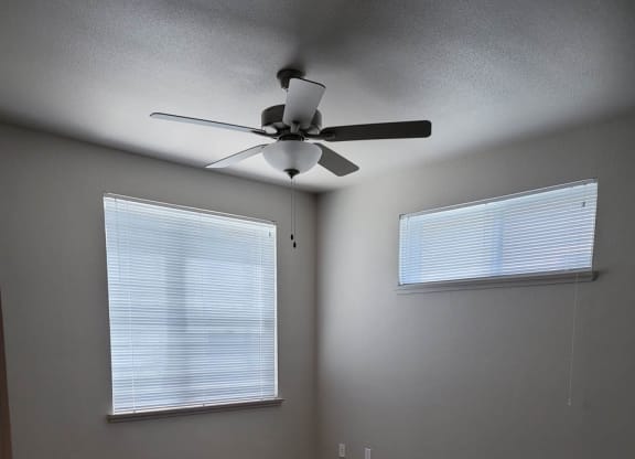 Bedroom with large windows and ceiling fan.