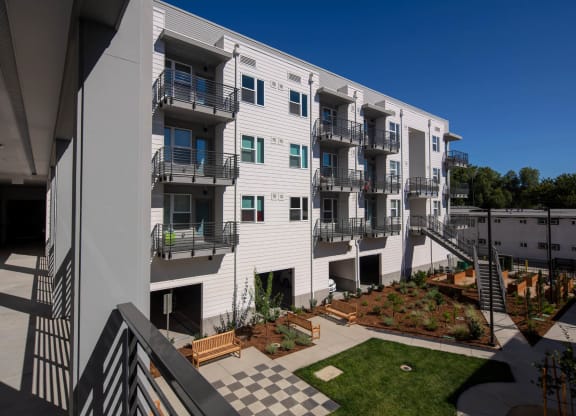 Interior courtyard from balcony, looking down on green space, exterior staircase, and garden.