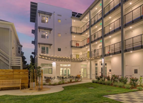 Interior courtyard at dusk with string lights and walkway lights illuminating courtyard.