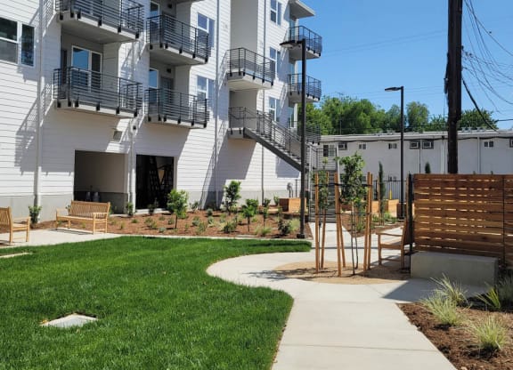 Courtyard at Lavender with large green space, walkways, and 4 story white building.