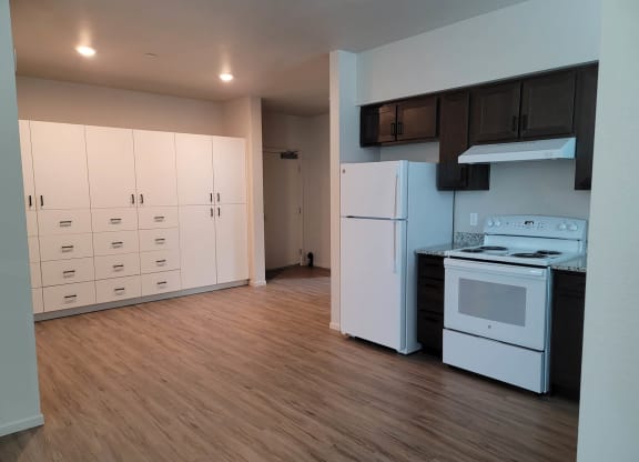 Kitchen with dark wood cabinets and white appliances, white built in pantry cabinets, and wood floors.