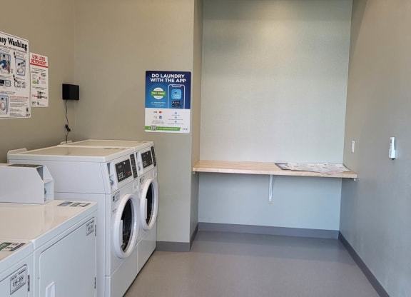 Laundry room at Lavender with two washing machines and dryers and a folding table.