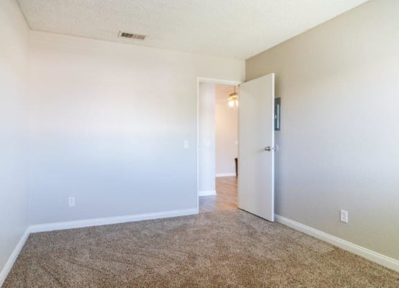 an empty living room with a door open to a hallway