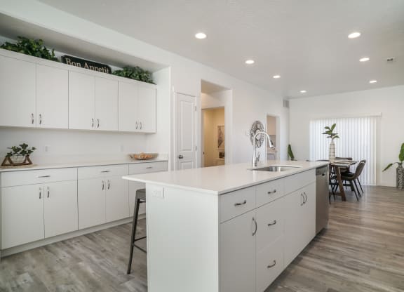 a kitchen with white cabinets and a large white island with a stainless steel sink