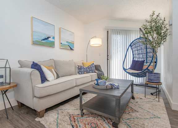 A living room with a white couch, a coffee table, and a hanging chair.