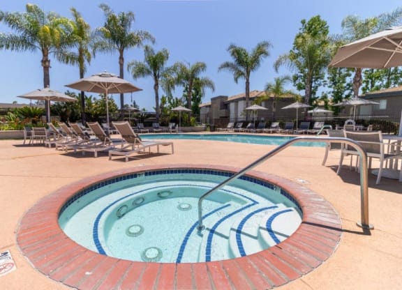 a hot tub in a pool with chairs and umbrellas