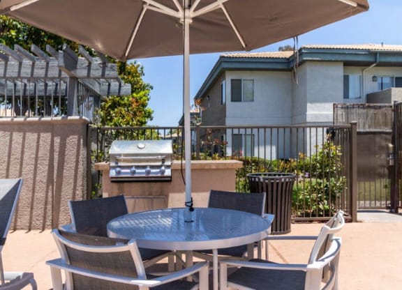 a patio with a table and chairs and a grill