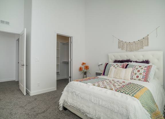a bedroom with white walls and a bed with a blanket and pillows