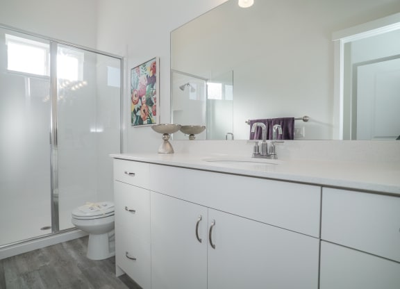 a bathroom with white cabinets and a glass shower
