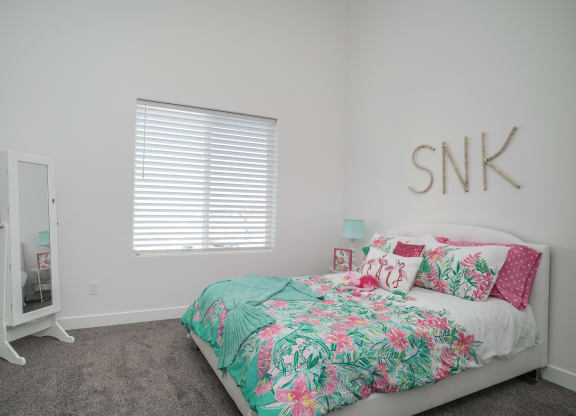 a bedroom with a bed with a tropical bedspread and pillows