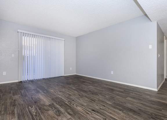 A room with wooden flooring and a window with blinds.