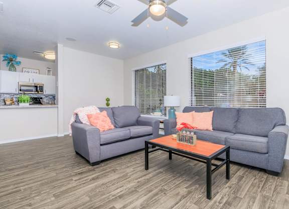 A living room with a grey couch, a coffee table, and a ceiling fan.