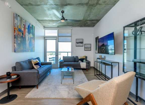A living room with a grey couch and a wooden chair.